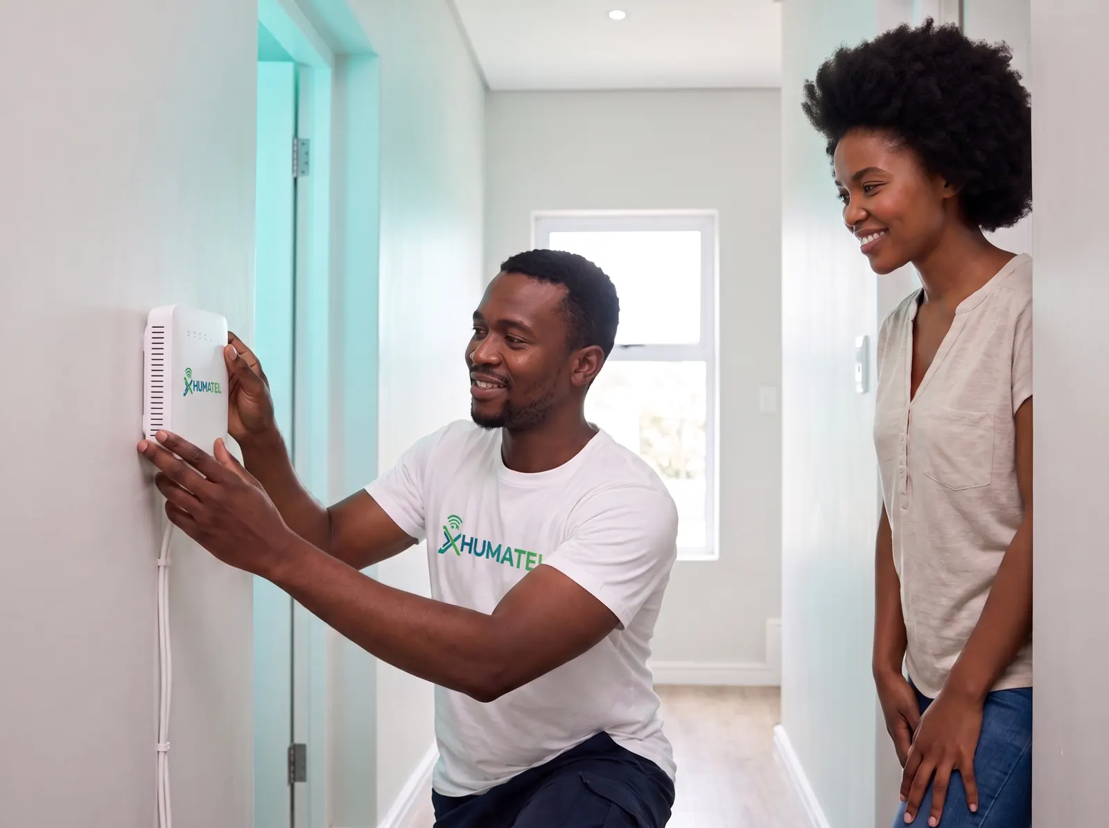 An Xhumatel technician mounting a white Xhumatel router on a wall